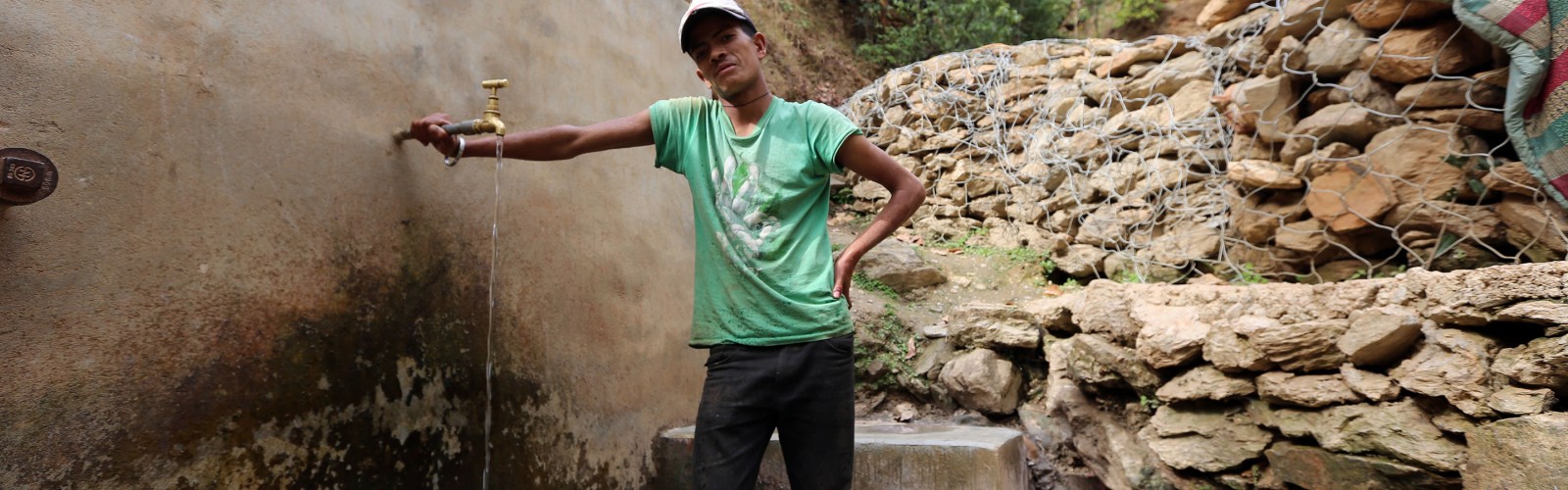 A young man collects water from a spring in Nepal.