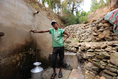 A young man collects water from a spring in Nepal.