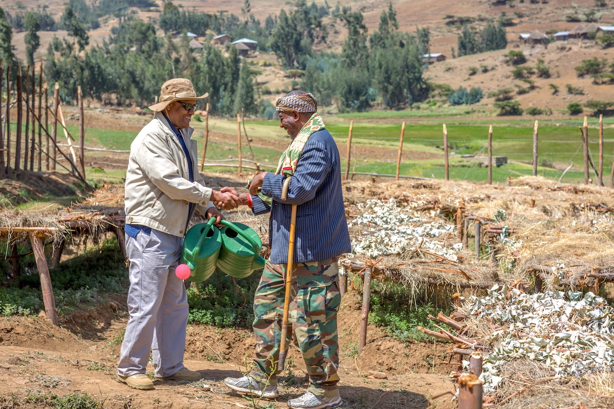 Wollo University’s Dr. Asmare hands over watering cans to farmer Mohammed Said, to signify the handover of the project to the community.