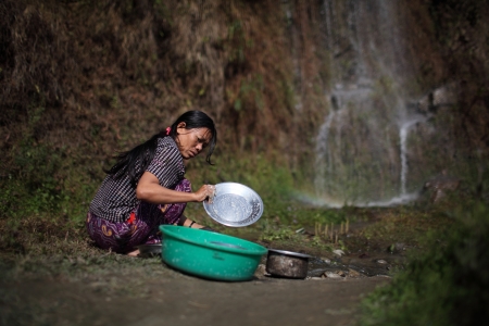A woman uses water from a spring for daily needs.