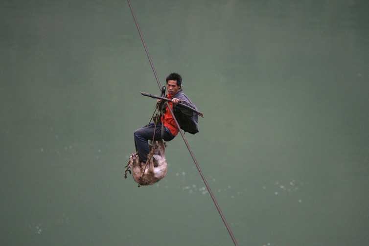A man and his goat cross over the Nu River on a cable, near Lushui southwest China’s Yunnan province. A man and his goat cross over the Nu River on a cable, near Lushui southwest China’s Yunnan province.